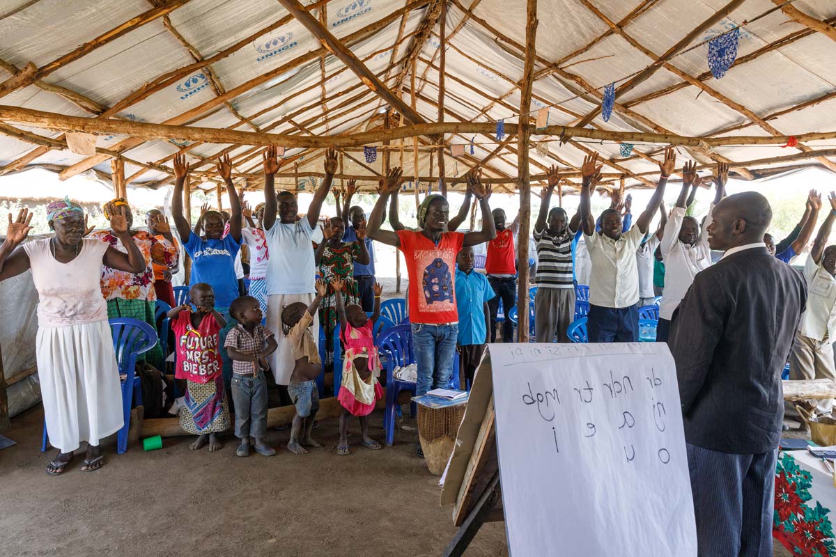 Uganda group learning together, hands raised